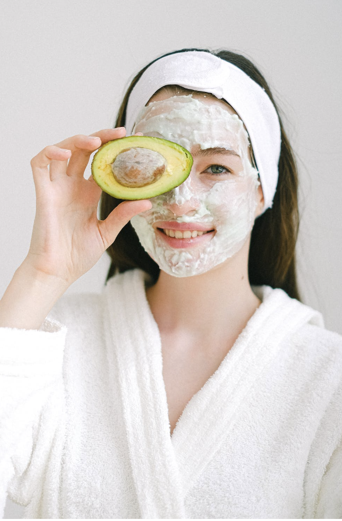 Asian girl holding avocado, using avocado as a beauty product